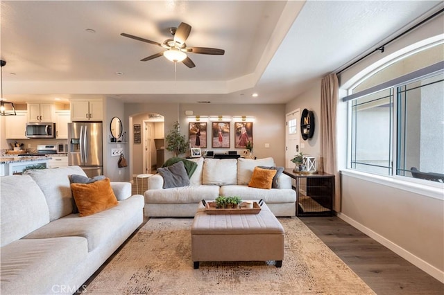 living area with wood finished floors, recessed lighting, arched walkways, baseboards, and ceiling fan