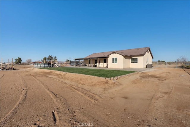 view of front facade with stucco siding, central AC, a patio, and fence