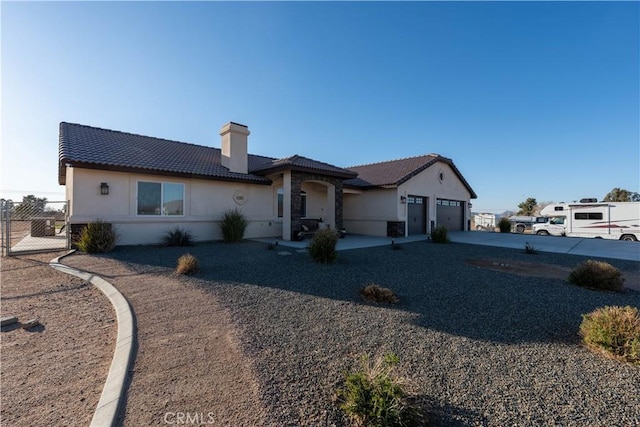 exterior space with stucco siding, a tile roof, fence, an attached garage, and a chimney