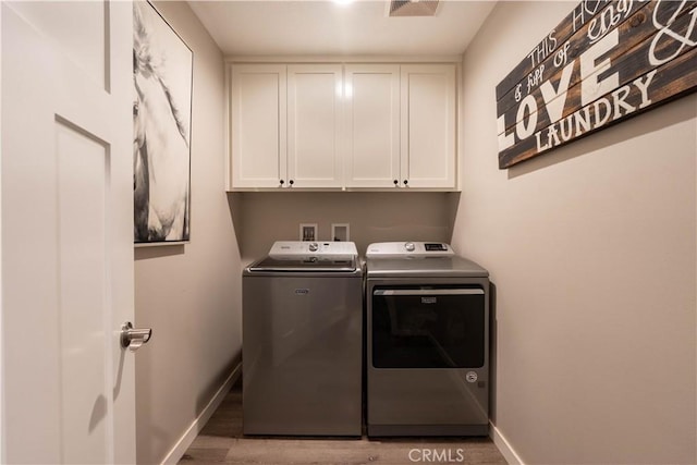 washroom with cabinet space, independent washer and dryer, light wood finished floors, and baseboards