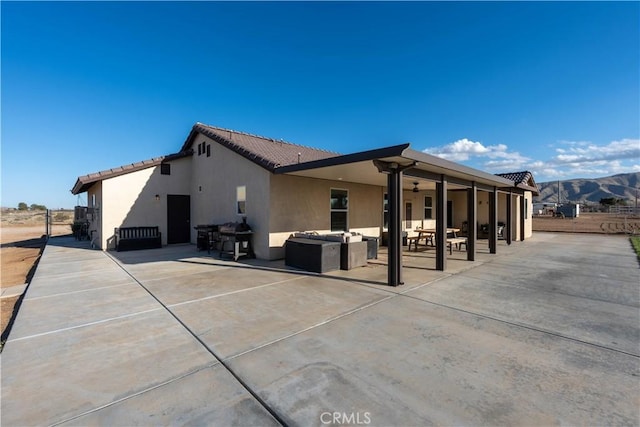 rear view of property featuring stucco siding, a mountain view, a patio area, an outdoor hangout area, and a tiled roof