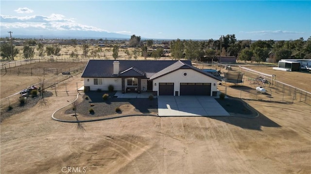 view of front of house with an attached garage, fence, stucco siding, a chimney, and driveway