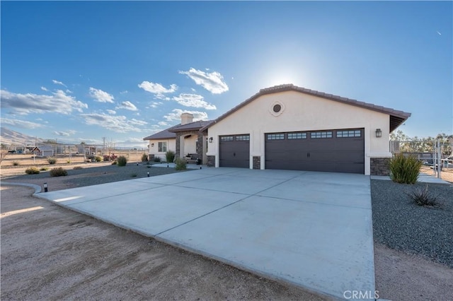 mediterranean / spanish-style house featuring stone siding, stucco siding, driveway, and a garage