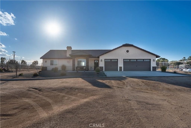 ranch-style home with fence, concrete driveway, stucco siding, a chimney, and an attached garage