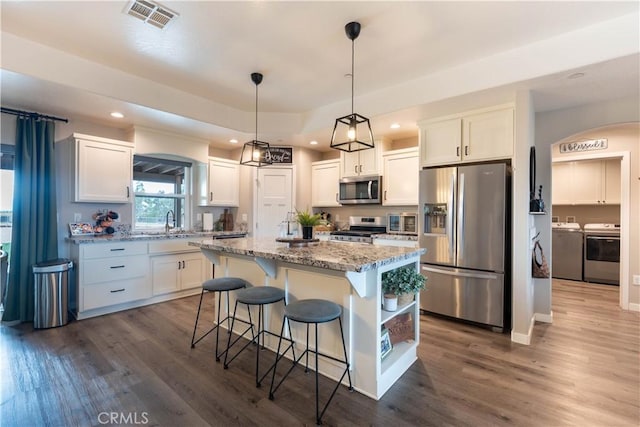 kitchen with visible vents, washer and dryer, dark wood-style floors, white cabinetry, and appliances with stainless steel finishes