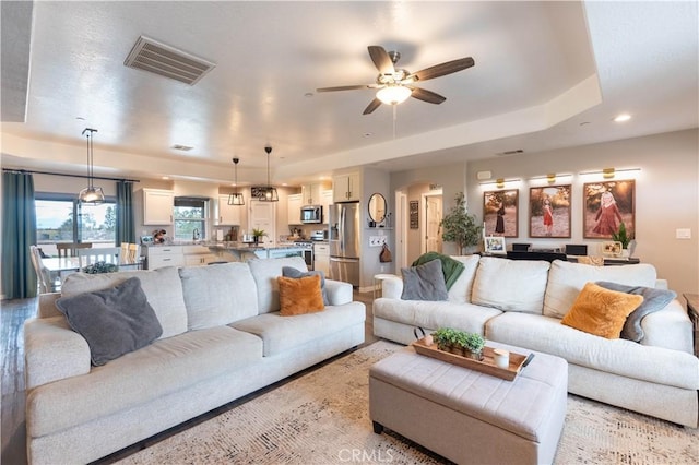 living room with visible vents, recessed lighting, arched walkways, a raised ceiling, and ceiling fan