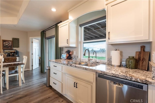 kitchen with light stone countertops, stainless steel dishwasher, wood finished floors, white cabinetry, and a sink