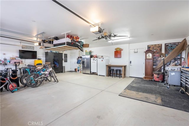 garage featuring a garage door opener, freestanding refrigerator, and stainless steel refrigerator with ice dispenser