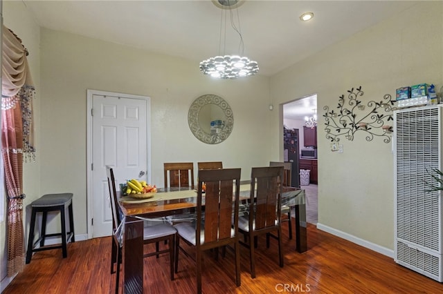 dining room featuring a notable chandelier, a heating unit, baseboards, and wood finished floors