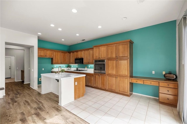 kitchen featuring oven, brown cabinetry, black microwave, and white gas stovetop