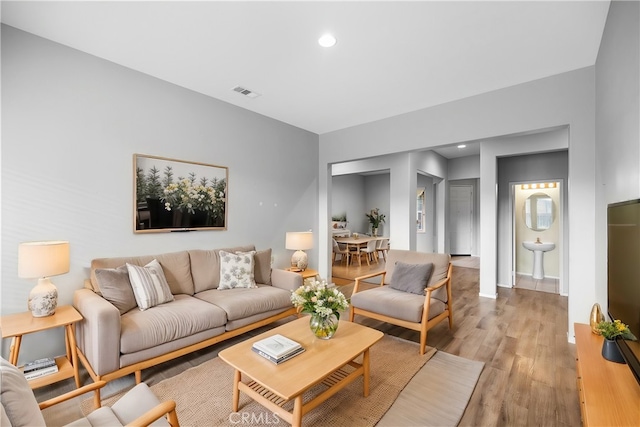 living room with recessed lighting, visible vents, and wood finished floors