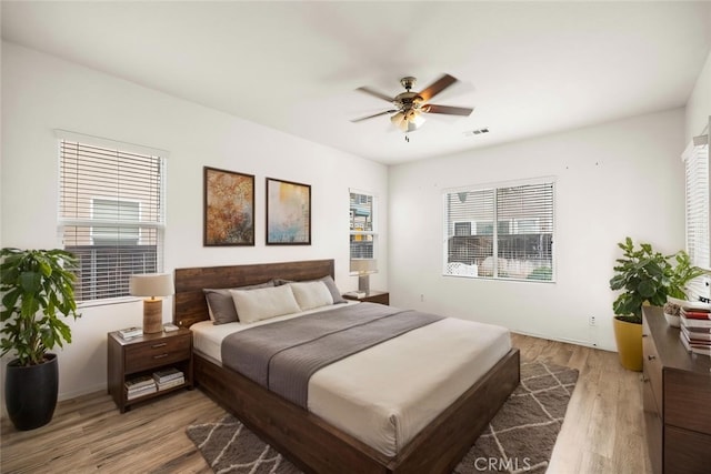 bedroom featuring light wood-style floors, visible vents, and ceiling fan