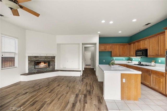 kitchen with light countertops, brown cabinetry, visible vents, and black microwave