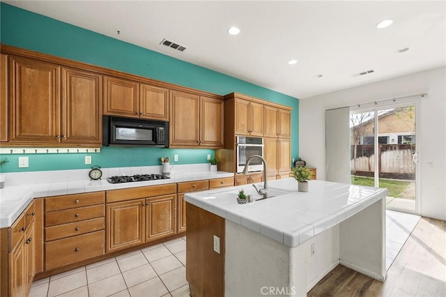 kitchen with visible vents, brown cabinets, black appliances, a sink, and recessed lighting