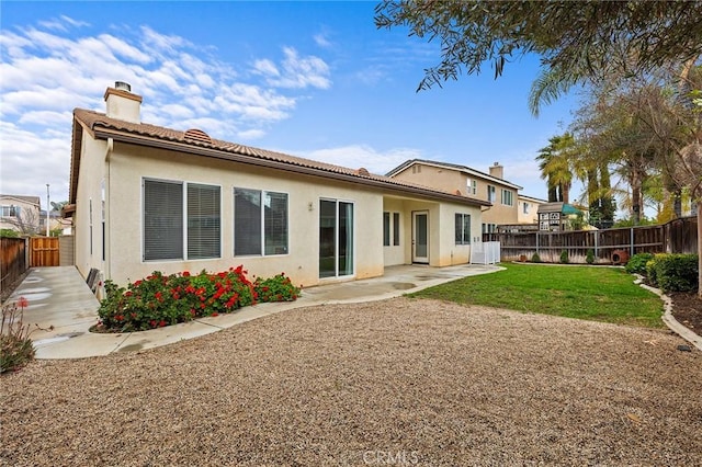 rear view of property featuring stucco siding, a patio, a fenced backyard, and a chimney