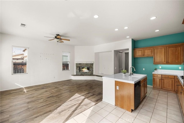 kitchen with brown cabinetry, visible vents, ceiling fan, dishwasher, and a wealth of natural light