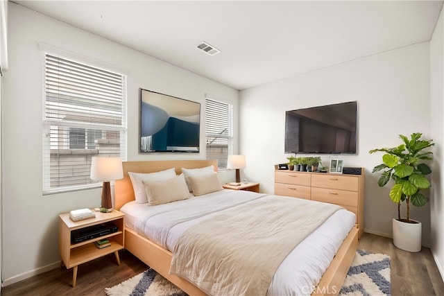 bedroom featuring visible vents, baseboards, and wood finished floors