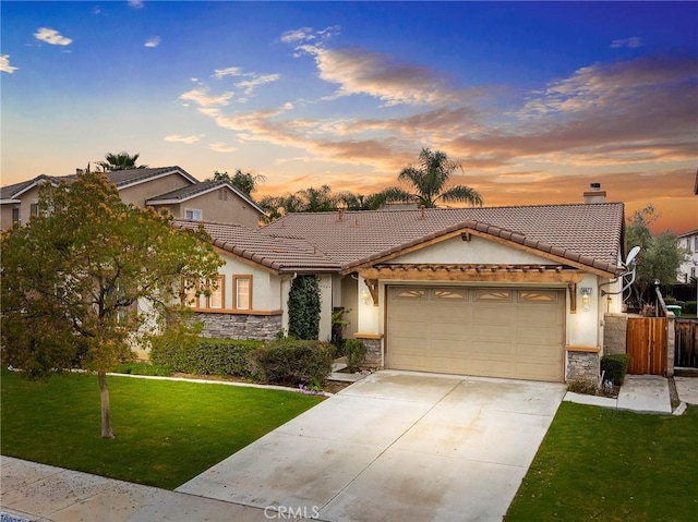 ranch-style home featuring driveway, a tile roof, stone siding, a yard, and an attached garage