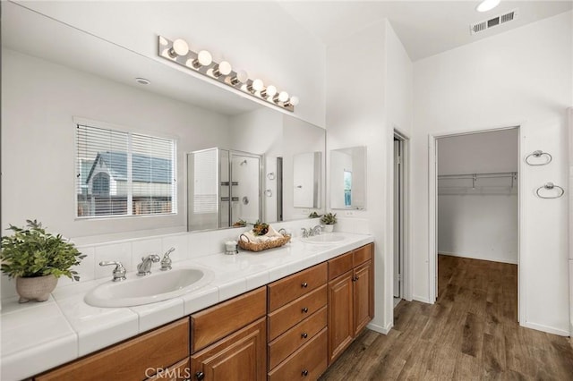 bathroom featuring visible vents, a shower stall, wood finished floors, and a sink