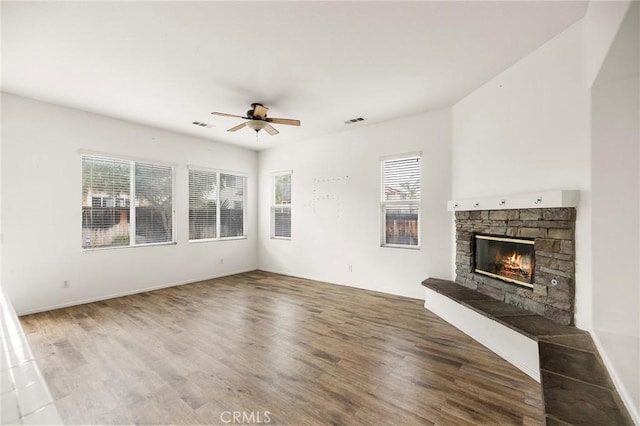 unfurnished living room with a fireplace, wood finished floors, visible vents, and a ceiling fan