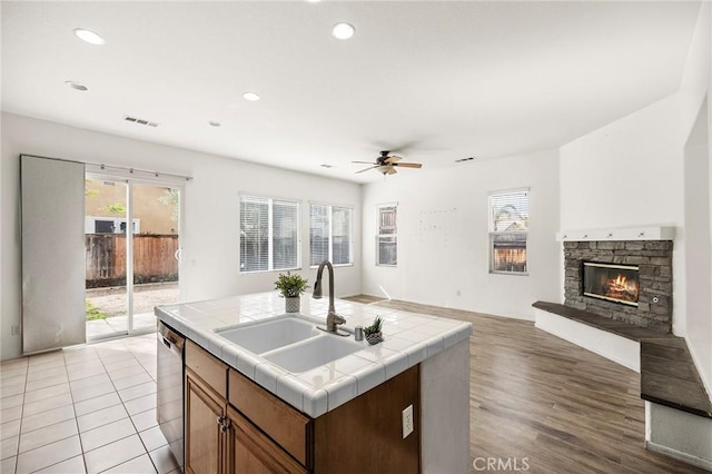 kitchen with visible vents, tile counters, open floor plan, dishwasher, and a sink