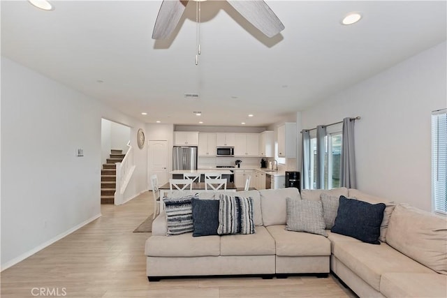 living area featuring light wood finished floors, stairway, recessed lighting, and baseboards