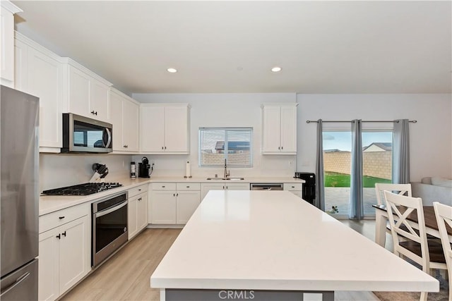 kitchen with light countertops, white cabinets, appliances with stainless steel finishes, and a sink