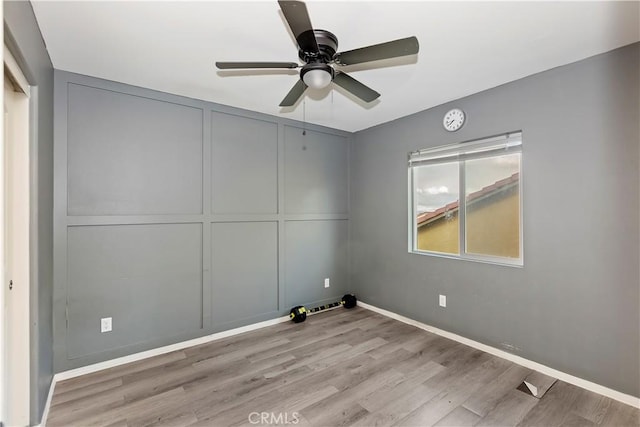 unfurnished bedroom with a ceiling fan, baseboards, light wood-style flooring, a closet, and a decorative wall