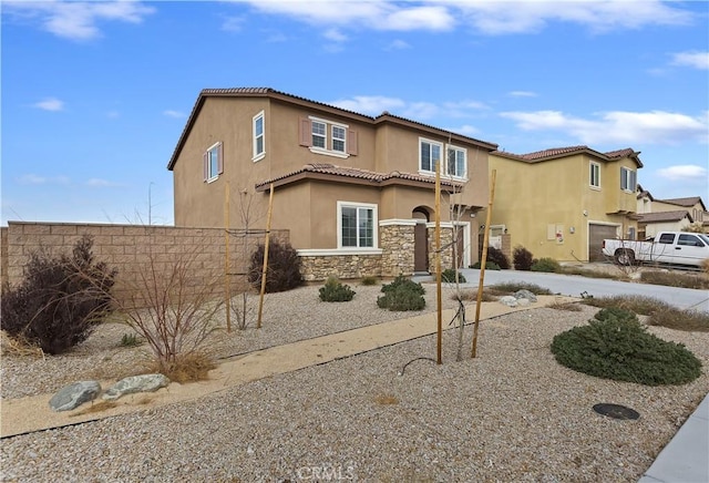 mediterranean / spanish home with fence, driveway, stucco siding, a garage, and stone siding