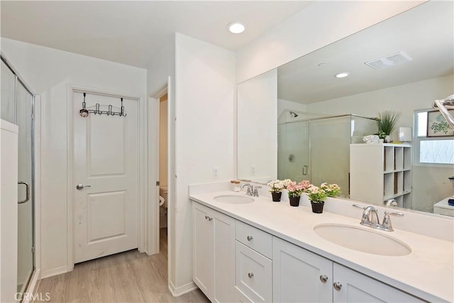 full bath featuring visible vents, a stall shower, wood finished floors, and a sink