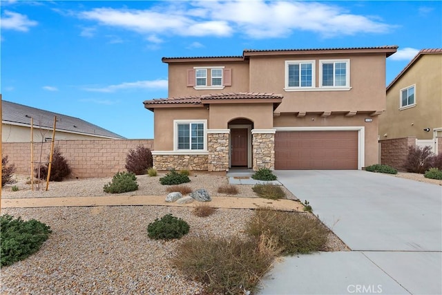 mediterranean / spanish-style home with concrete driveway, fence, stone siding, and stucco siding