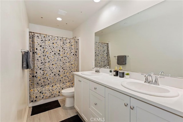 bathroom with a shower with curtain, double vanity, toilet, and a sink