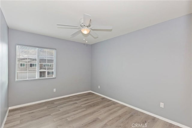 empty room featuring a ceiling fan, baseboards, and light wood finished floors