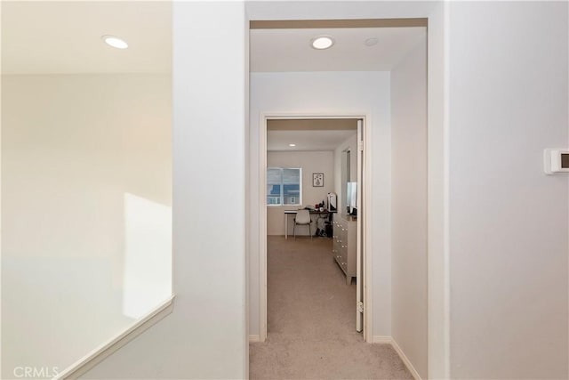 hallway with recessed lighting, light colored carpet, and baseboards