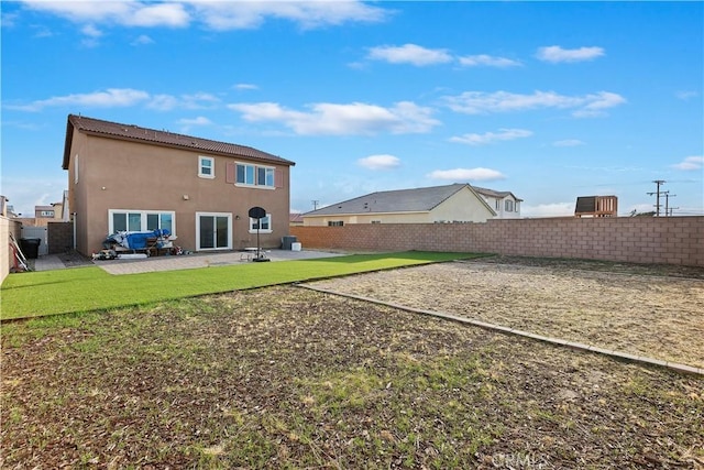 rear view of property featuring a patio area, a yard, a fenced backyard, and stucco siding