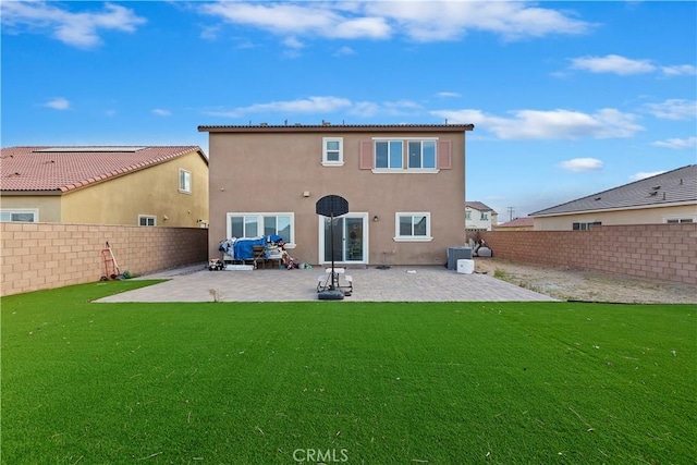 rear view of property with a fenced backyard, stucco siding, a lawn, and a patio