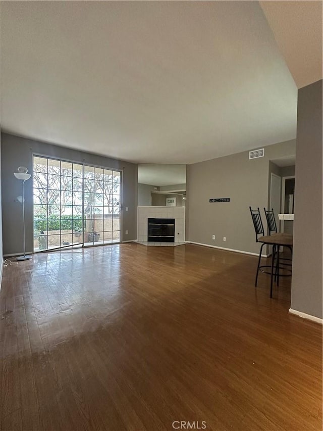 unfurnished living room with visible vents, baseboards, and dark wood-style flooring