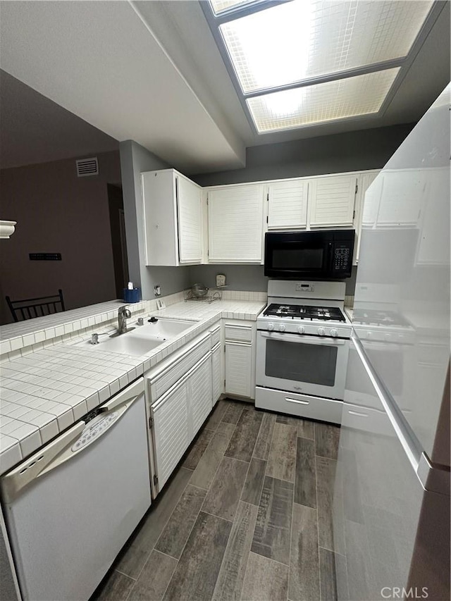 kitchen featuring visible vents, wood finish floors, white appliances, white cabinetry, and a sink