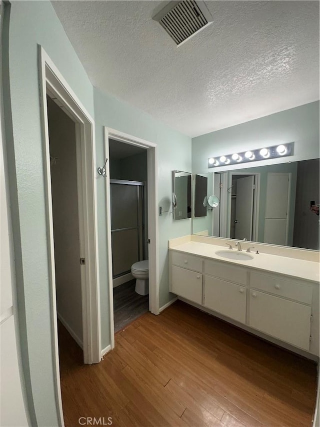 full bath with visible vents, toilet, a stall shower, wood finished floors, and vanity