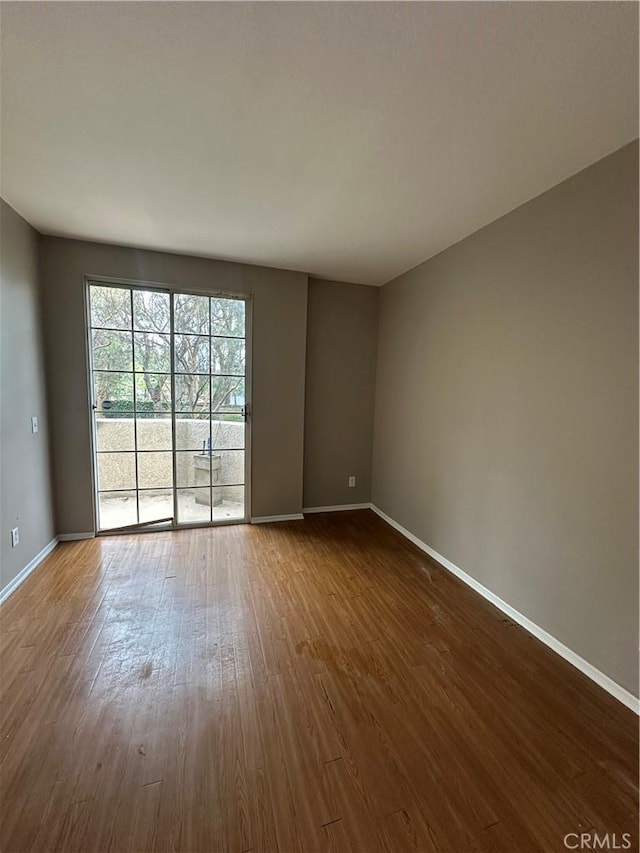 spare room featuring dark wood finished floors and baseboards