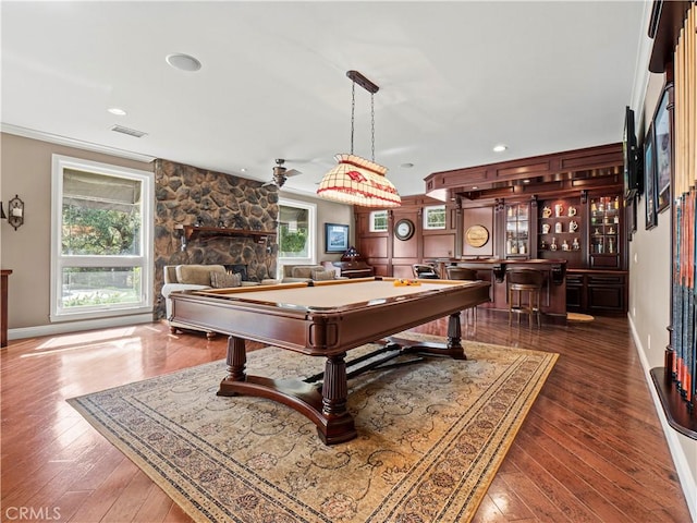 recreation room with baseboards, hardwood / wood-style floors, a stone fireplace, wet bar, and billiards