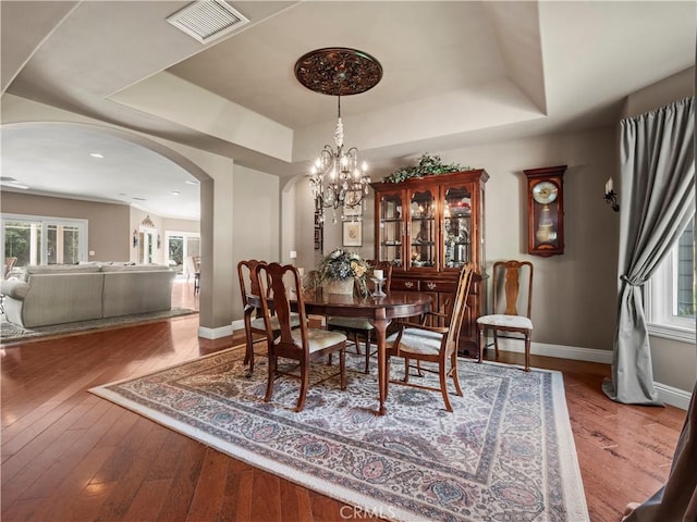 dining area featuring a raised ceiling, baseboards, visible vents, and arched walkways