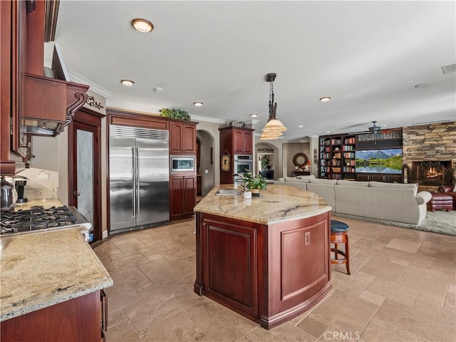 kitchen featuring a sink, built in appliances, arched walkways, and reddish brown cabinets