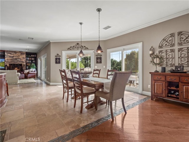 dining room featuring visible vents, baseboards, ornamental molding, and a fireplace