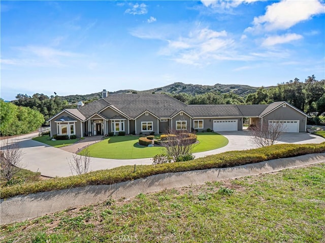 view of front of property featuring a mountain view, an attached garage, concrete driveway, and a front yard