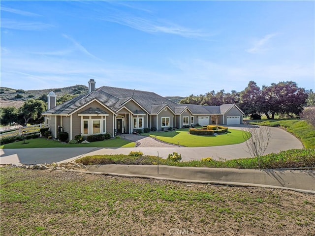 view of front of house featuring a chimney, an attached garage, concrete driveway, and a front lawn