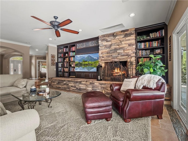 living area with stone finish flooring, crown molding, a stone fireplace, recessed lighting, and arched walkways