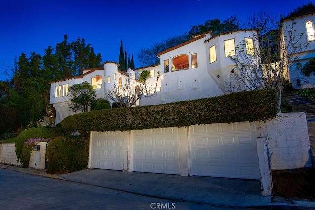 mediterranean / spanish home with a garage and stucco siding