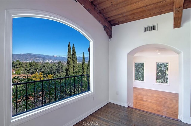 interior space with visible vents, beam ceiling, wood finished floors, a mountain view, and baseboards