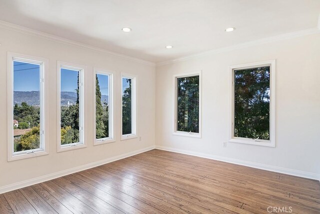unfurnished room featuring baseboards, ornamental molding, and hardwood / wood-style flooring